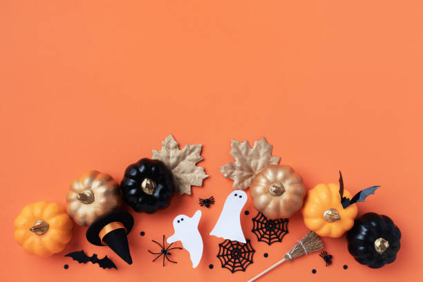 istock Halloween holiday frame with party decorations from pumpkins, bats, spider web and ghosts top view. Happy halloween greeting card on orange. 2168160491