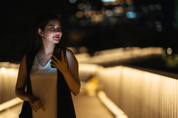 istock Female in City at Night Using Smartphone – Urban Technology, Digital Communication, and Nightlife Scene 2168160890