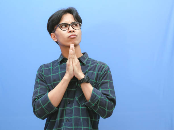istock Asian man showing thinking gesture with his eyes looking up on isolated blue background 2168165144