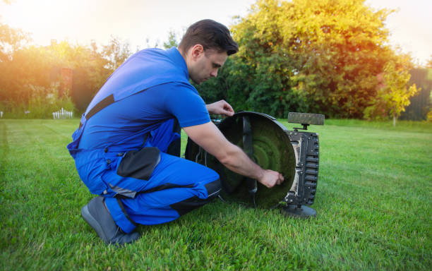 istock Man in blue overalls is carefully adjusting a lawn mower blade and cleaning while kneeling on a well-kept lawn. The importance of proper equipment maintenance for effective lawn care. 2168175441