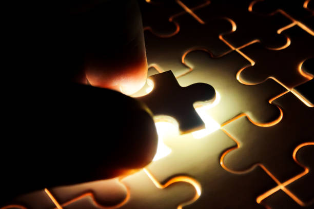 close-up of a hand holding a glowing jigsaw puzzle piece
