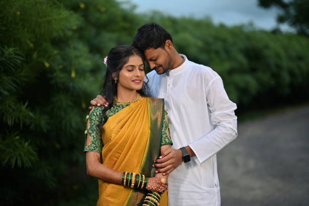 Candid portrait of a young couple dressed in a traditional attire for their haldi ceremony A candid portrait capturing the joyful connection between a young couple dressed in traditional Indian attire for their Haldi ceremony. The bride radiates happiness in her bright yellow saree, while the groom looks charming in his traditional white kurta. haldi ceremony stock pictures, royalty-free photos & images