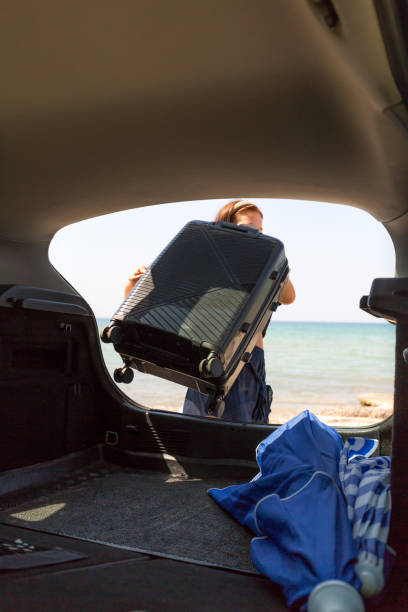 istock Girl with large black suitcase putting it in the trunk 2168187637