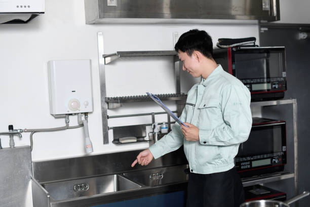 A male worker inspecting the water supply equipment (sink) in the kitchen