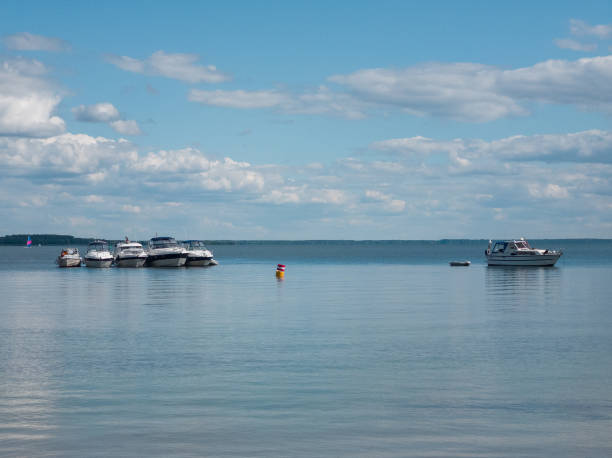 istock Boats moored on a calm lake under a blue sky with white clouds 2168194632