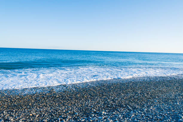 istock Crystal Blue Waves Gently Embrace the Pebbled Shore 2168194703