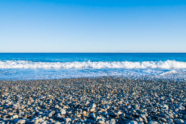 istock Crystal Blue Waves Gently Embrace the Pebbled Shore 2168194963