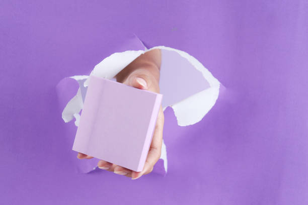 Female Hand Holding a Package Purple Sticky Notes on RIped Paper Background
