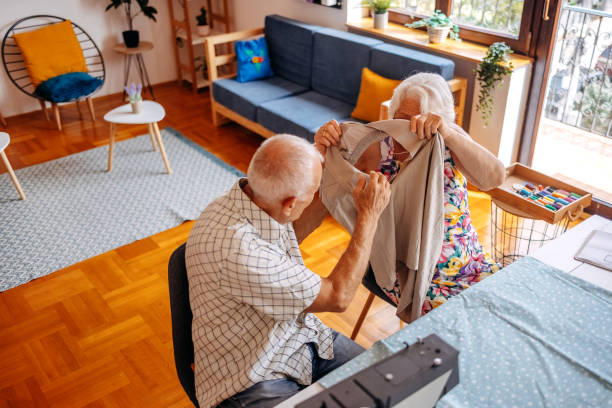 istock Old couple repairing hole on pants together using sewing machine at home 2168201393