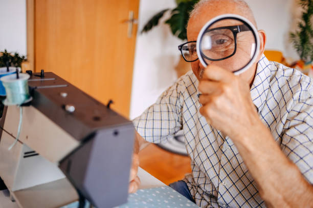 istock Old couple repairing clothes together using sewing machine at home and using magnifying glass 2168201864