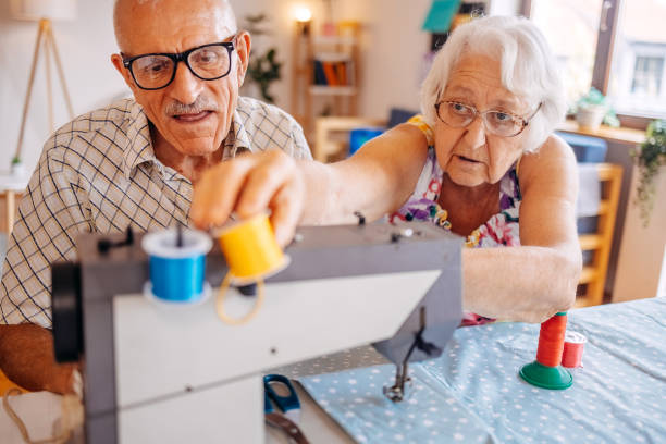 istock Old couple repairing clothes together using sewing machine at home 2168201956