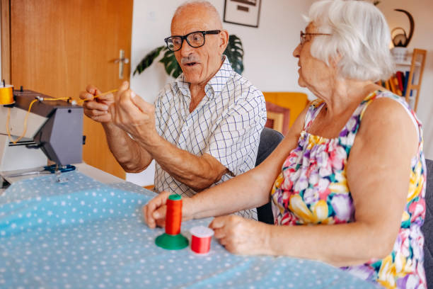 istock Old couple repairing clothes together using sewing machine at home 2168202040