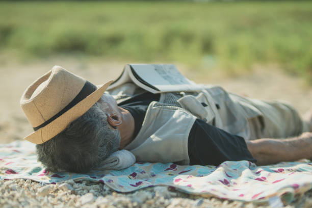 Man in straw hat sleeping in the shade of a tree in hot weather.