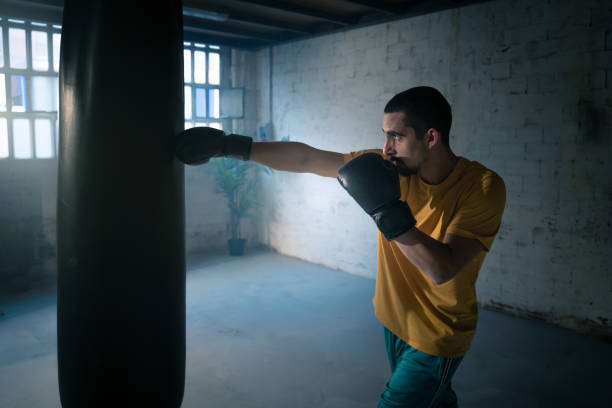 istock Fighter hits punching bag in a dark gym. 2168215669