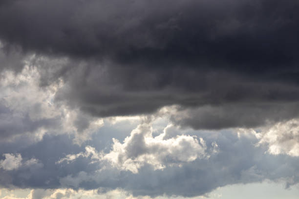 istock Beautiful dramatic sky background with stormy clouds before a thunderstorm with sunlight. Dark gray clouds floating in the bright sunny sky. 2168220490