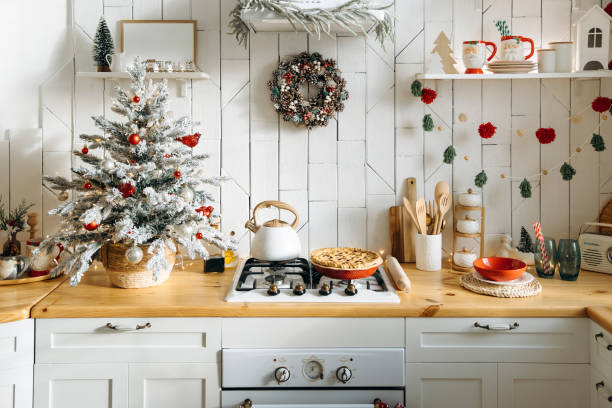 istock Festive kitchen featuring a small frosted Christmas tree, a pinecone wreath, red and white ornaments, and a freshly baked pie on the counter, creating a warm holiday atmosphere 2168225522