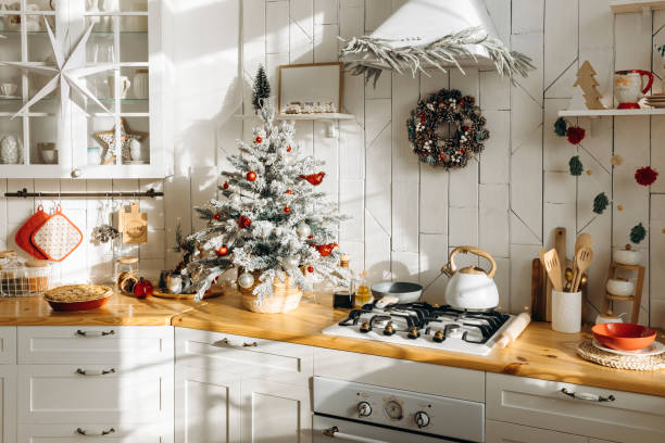 istock Bright kitchen decorated for Christmas with a frosted mini tree adorned with red and white ornaments, a festive wreath on the wall, and various kitchen items on the counter 2168226760