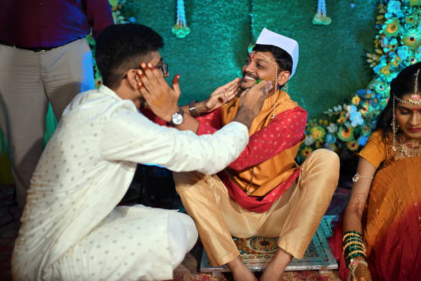 An Indian Haldi ceremony, showcasing the groom and his cousin joyfully applying turmeric paste to each other. This candid moment beautifully captures the close bond between the groom and his cousin, as well as the fun and communal spirit of the Haldi ritual.
