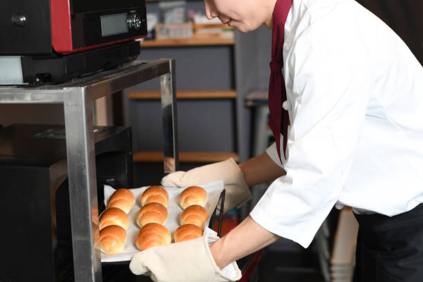 Young man making bread in the oven in the kitchen