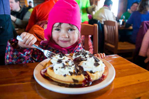 Young girl eats waffles in ski lodge, Whistler, B.C.