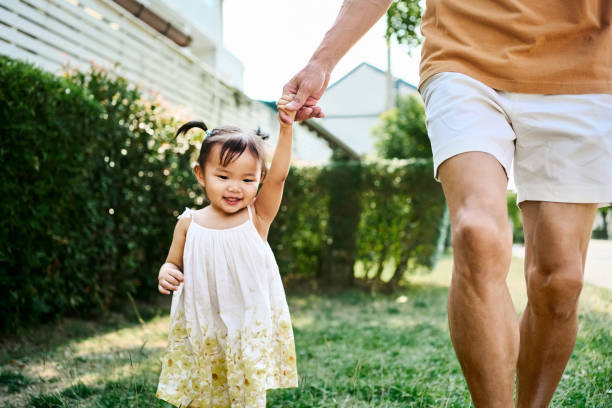 istock Father running with daughter on lawn outside their home 2168270199