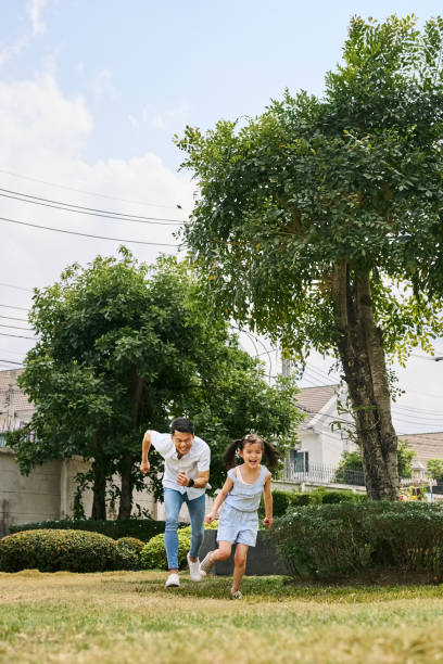 istock Dad chasing little girl running at park 2168270307