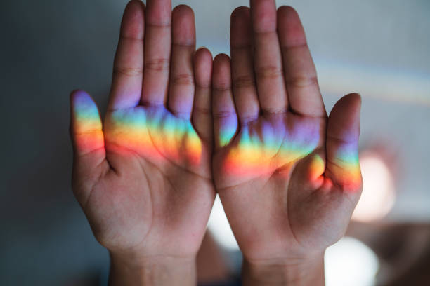 Close-up of two hands with a vibrant rainbow reflection across the palms.