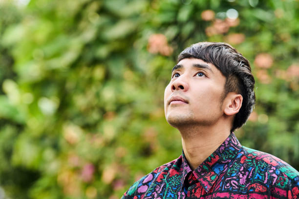 istock Stylish young man looking up while standing outside on a street 2168277474