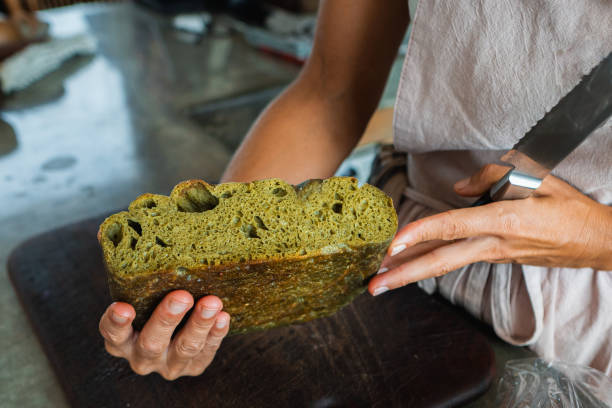 Baker woman holding freshly baked green vegan bread loaf