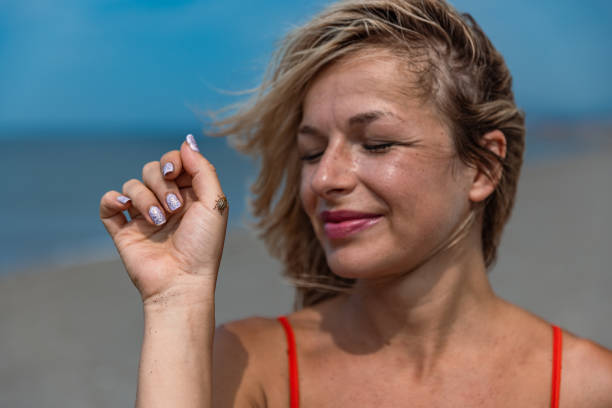 Happy Blonde Woman Smiling at a Bug on Her Hand - Stock Photo
