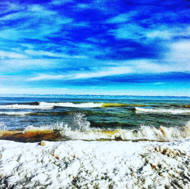This captivating photograph captures the dynamic beauty of Lake Michigan during winter in Glenview. The image showcases the contrast between the frothy, snow-covered shoreline and the vibrant, blue sky above. The waves crash energetically against the icy shore, creating a stunning interplay of movement and stillness. The scene is both serene and powerful, highlighting the unique charm of Lake Michigan in the colder months. This photograph is a testament to the natural beauty and seasonal transformations of this iconic Great Lakes.