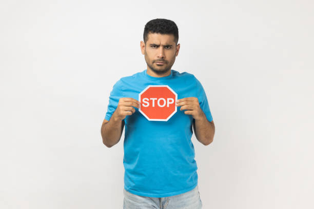 istock Strict man holding red stop sign, looking at camera with negative aggressive expression, showing ban 2168287781