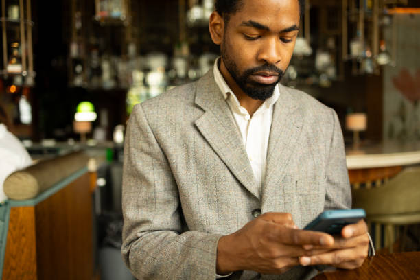istock A focused businessman in a grey suit uses his smartphone while sitting in a stylish, modern cafe. The image captures professional ambiance and technological engagement in a relaxed environment. 2168287995