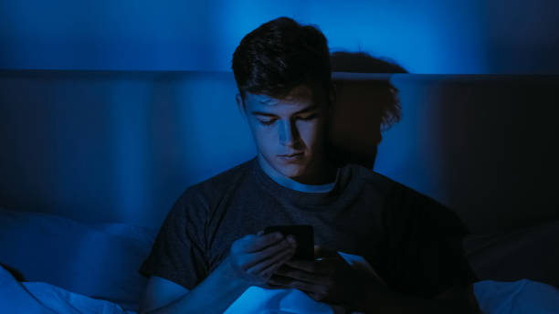 istock Insomnia Concept Young Man with Phone in Dark Room 2168288372