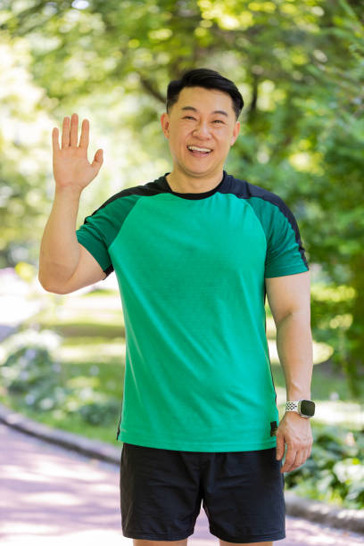 istock Athletic runner sport man waving hi hello welcome with hand greeting with hospitable friendly smile 2168288901