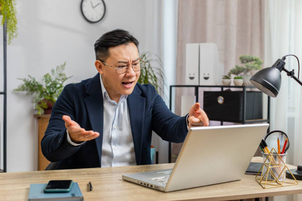 Angry businessman CEO making laptop call conversation at home office, quarrel conflict negotiation