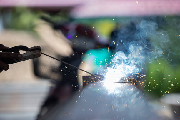 A man is holding a welding torch and sparks are flying. Concept of danger and excitement, as the man is working with a potentially hazardous tool. The sparks and heat from the torch create a dramatic