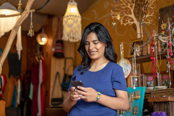 istock woman using smartphone while working or shopping at clothing store boutique 2168308737