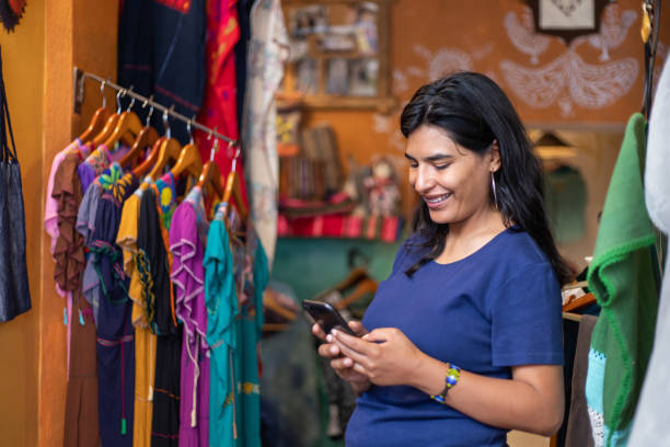 istock woman using smartphone while working or shopping at clothing store boutique 2168308742