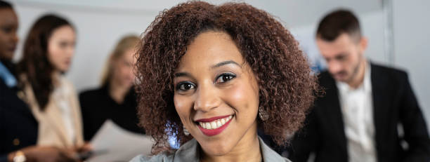 istock Horizontal banner or header with smiling south american business woman working inside modern office with the multiethnic team behind her - Concept of leadership and achieving goals - Focus on eyes 2168338451