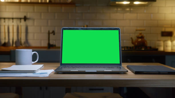 istock A laptop with a green screen with a tablet, coffee cup and documents on a wooden table, emphasizing productivity and organization. 2168338883