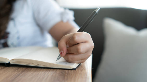 istock Little girl hand writing notes in notebook at home 2168339097