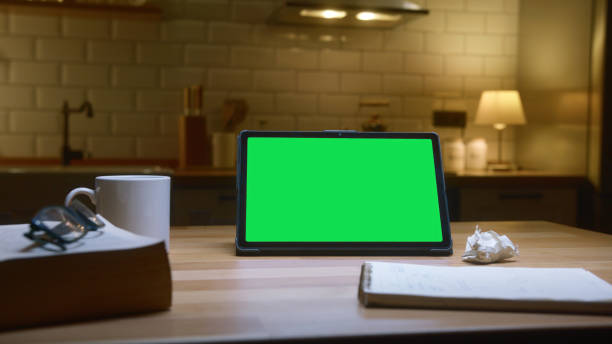 istock Tablet computer with green mock up green screen on table with a book and notebook in the cozy kitchen. 2168340226