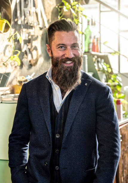 istock Confident businessman with a full beard smiling in a modern office setting. He is dressed in a professional suit and vest with a cheerful expression. 2168345083