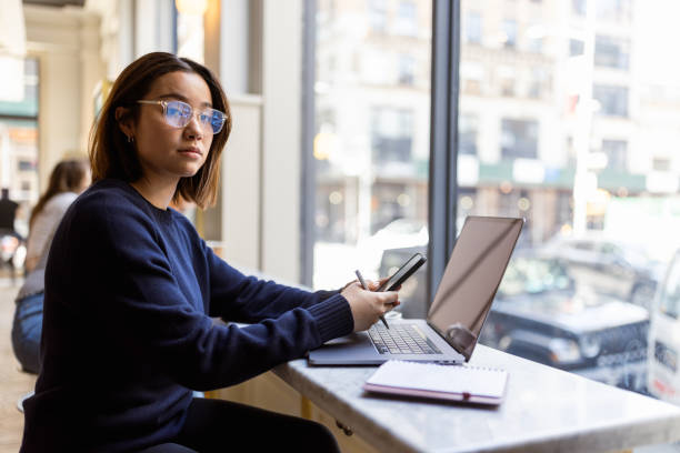 istock Young Woman Working on Laptop by Window in Cafe 2168350543