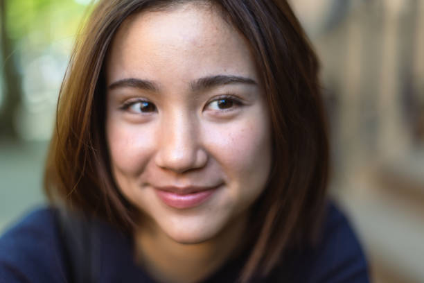A close-up of a young woman with a happy expression and soft smile captured in natural daylight.