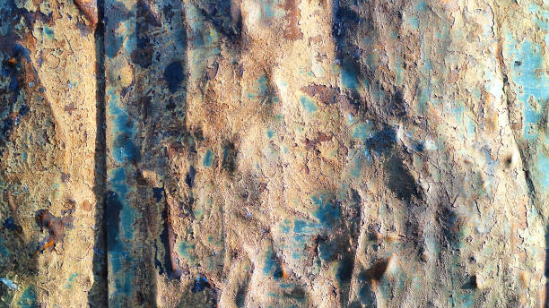 istock A heavily dented sheet metal illuminated by side light. Dents and bulges, peeling blue paint, scratches and rust are clearly visible. Background. Texture. 2168353896