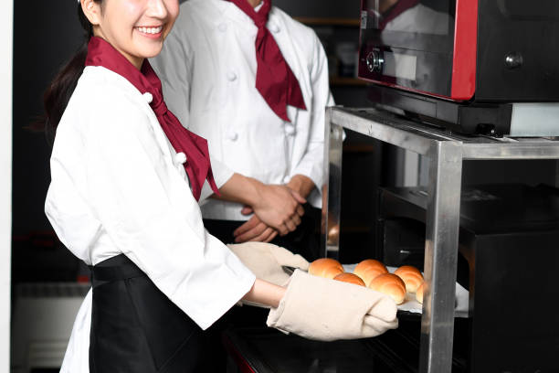 istock Young bakery women having a conversation while making bread in the oven in the kitchen 2168355010