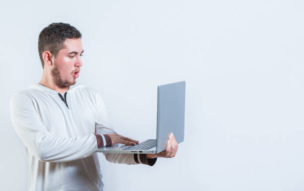 istock Surprised guy holding and looking at an promotion on laptop screen. Amazed handsome man standing using laptop isolated 2168359438