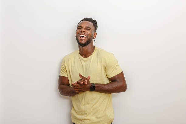 istock Happy man in a yellow shirt laughing heartily while standing against a plain background 2168360695